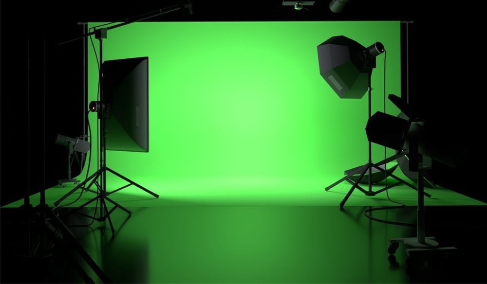 Professional green screen studio setup with lighting equipment on tripods against bright lime green backdrop